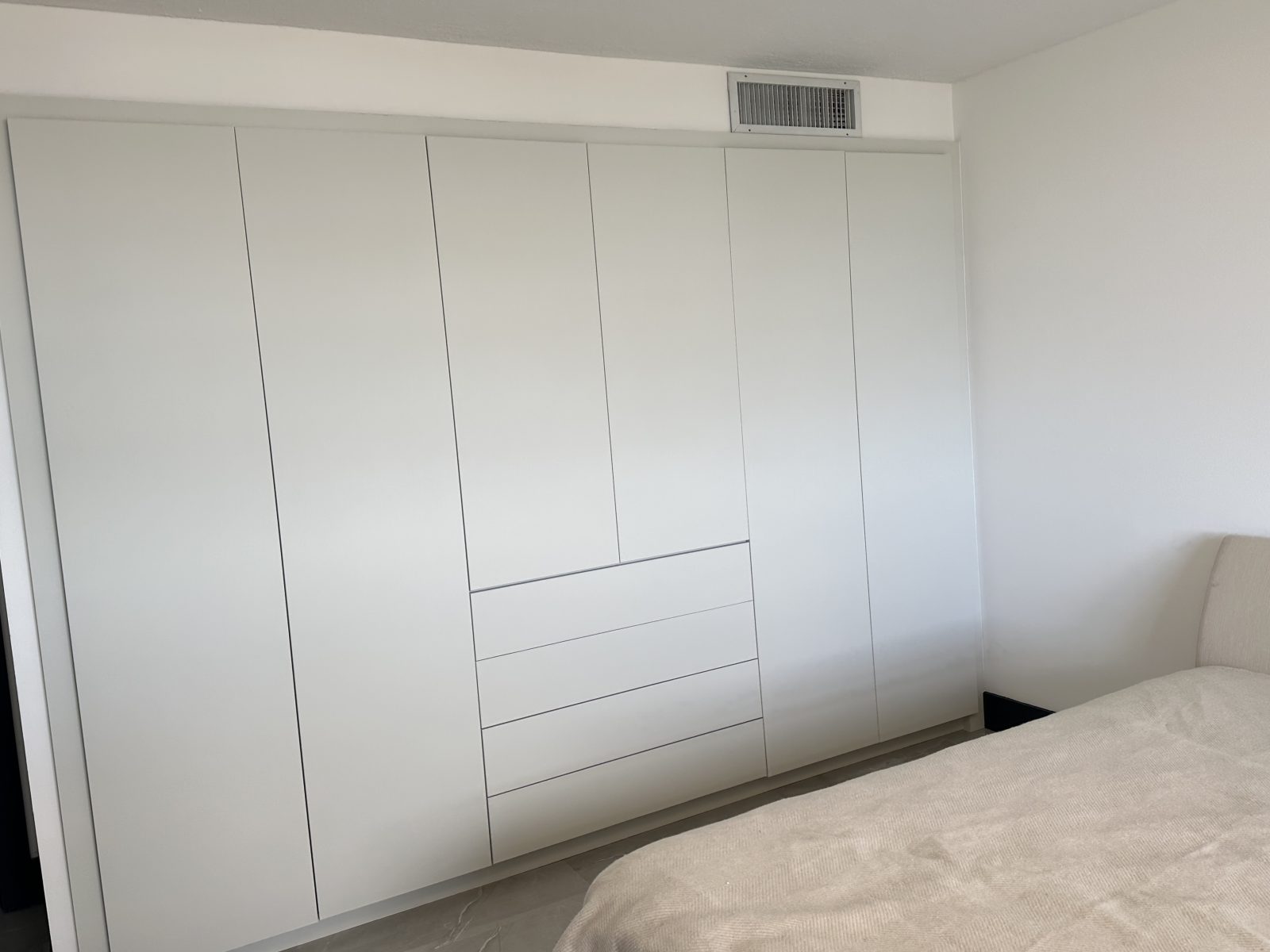 The same wardrobes wrapped in a matte white film, reflections gone and the joinery unchanged